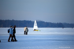 Eissegler und Spaziergänger auf zugefrorenem See