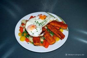 Fischstäbchen an Spiegelei auf Gemüsebeet